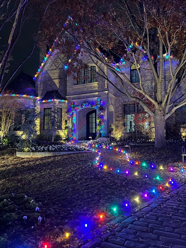 Multicolor pathway lights leading to a lit stone home