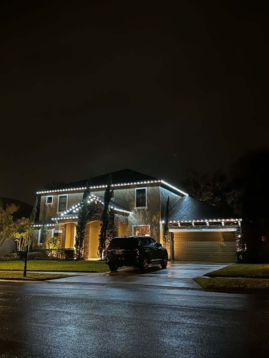 Large home with white roofline lights on a rainy night